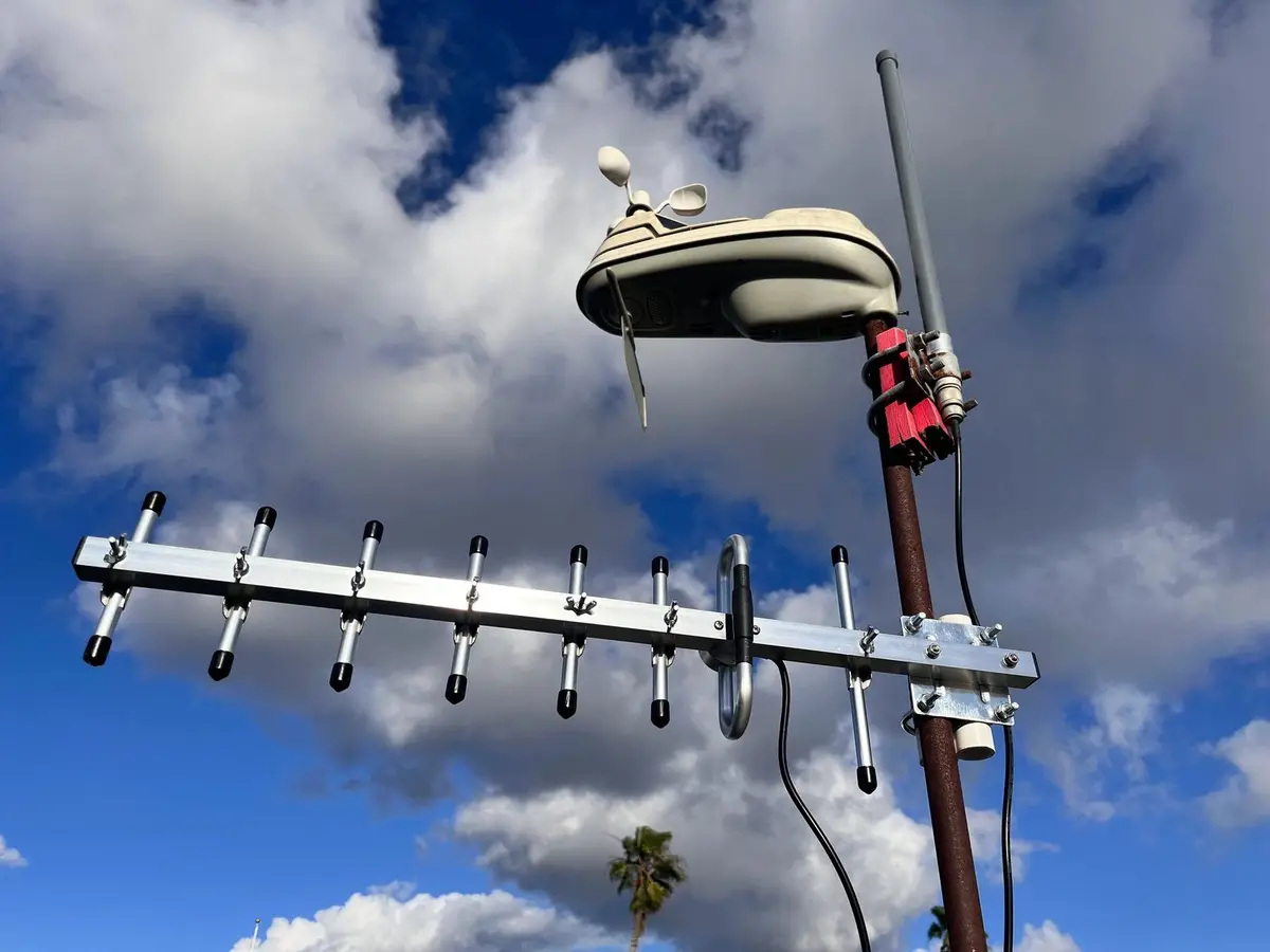 A directional Yagi antenna clamped to a mast, pointed into a blue sky