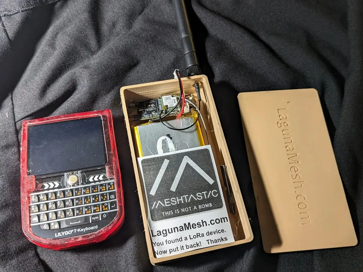 A keyboard handheld radio, a sticker and a battery pack on a dark cloth
